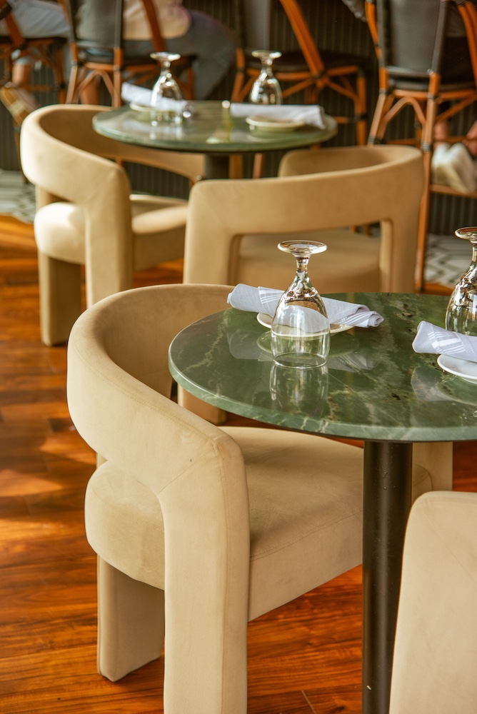 Green marble table with cream dining chairs prepared for dinner service